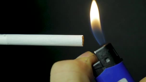 Hand lighting lighter cigarette closeup. Burning cigarette on black background. Cigarette closeup on black background — Stock Video