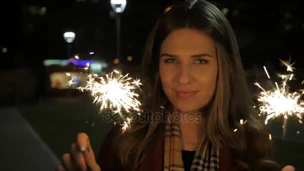 Jovem bela menina sorridente feliz segurando sparkler na rua. Conceito de férias. Menina com faíscas na rua — Vídeo de Stock