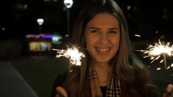 美しい幸せな笑みを浮かべて少女通りに線香花火を保持しています。休日のコンセプトです。通りで花火を女の子 — ストック動画
