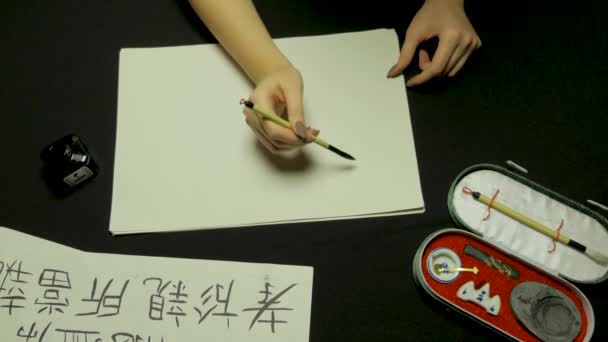 Les femmes écrivent à la main la calligraphie chinoise. Main féminine tenant un pinceau d'écriture caractères chinois — Video