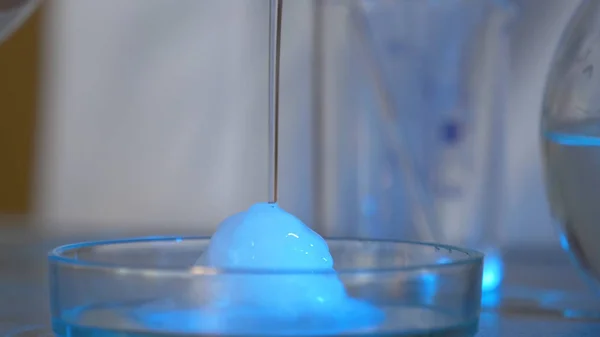Reacción química en frasco volumétrico de vidrio en laboratorio. El reactivo químico rosa en un frasco transparente. Reacción química de cerca — Foto de Stock