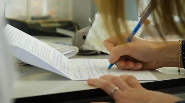 Närbild av en kvinnlig hand skriva på en tom anteckningsbok med en penna. Närbild av en kvinnlig hand skriva på en tom anteckningsbok med en penna — Stockfoto