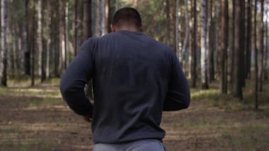 Orman yolda çalışan kas Çalıştırıcısı. Arkadan Görünüm. Orman yolda koşan atletik adam. Sonbahar orman ile iz üzerinde koşan atletik adam