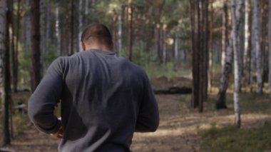 Orman yolda çalışan kas Çalıştırıcısı. Arkadan Görünüm. Orman yolda koşan atletik adam. Sonbahar orman ile iz üzerinde koşan atletik adam