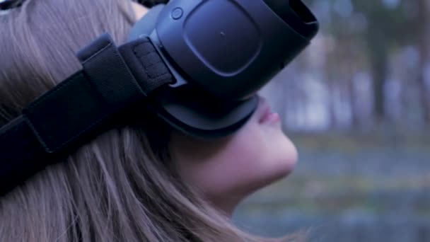 Hermosa mujer con realidad virtual en el parque al aire libre. Dispositivo de gafas VR. Mujer joven con gafas VR en el parque. Primer plano — Vídeos de Stock