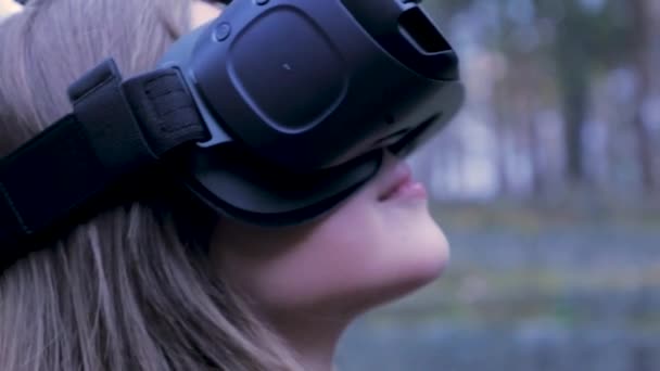 Красива жінка з віртуальною реальністю у відкритому парку. VR гарнітура окуляри пристрій. Молода жінка в окулярах VR в парку. Крупним планом — стокове відео