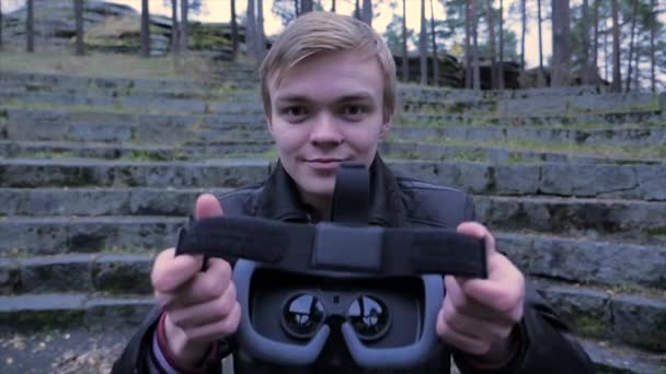 Νεαρός δώσει εικονική πραγματικότητα ακουστικά στο πάρκο. Νεαρός δώσει εικονική πραγματικότητα ακουστικά στην υπαίθρια — Αρχείο Βίντεο