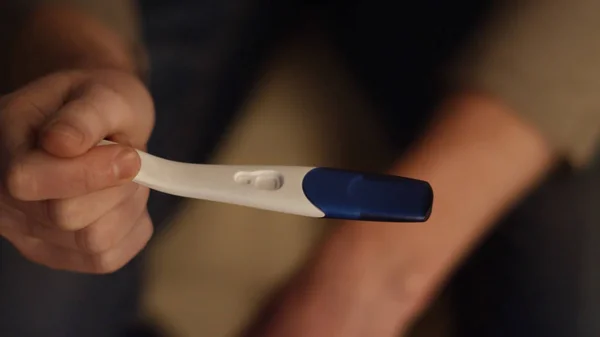 Male hand holding positive pregnancy test close up. Male hands holding a pregnancy test and put it. Man husband upset about pregnancy test results — Stock Photo, Image