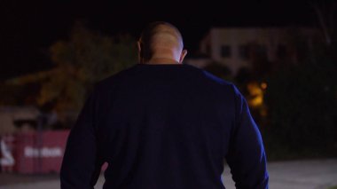 Kas yapı ayakta spor zemin arka plan ile uygun genç adam görünümünü arka. Avcı kopya alanı arıyor. Kaslı erkek geri