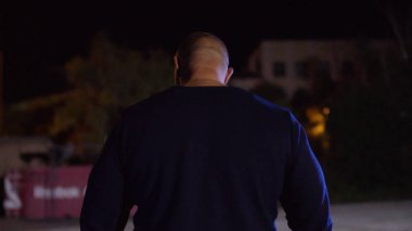 Kas yapı ayakta spor zemin arka plan ile uygun genç adam görünümünü arka. Avcı kopya alanı arıyor. Kaslı erkek geri