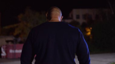 Kas yapı ayakta spor zemin arka plan ile uygun genç adam görünümünü arka. Avcı kopya alanı arıyor. Kaslı erkek geri