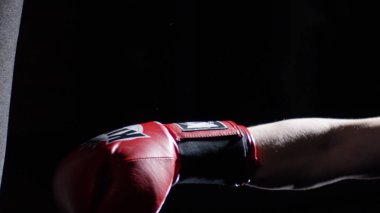 Kum torbası - adam ile A dövme boks üzerinde karanlık bir arka plan ile bazı başladı pratik savaşçısı. Tekme, koyu arka plan üzerinde kum torbası. Siyah kum torbası spor salonunda ağırlığında