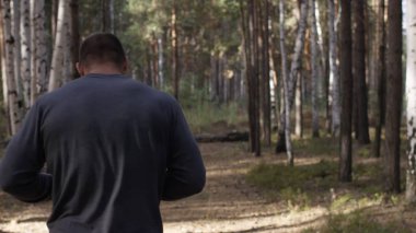 Orman yolda çalışan kas Çalıştırıcısı. Arkadan Görünüm. Orman yolda koşan atletik adam. Sonbahar orman ile iz üzerinde koşan atletik adam