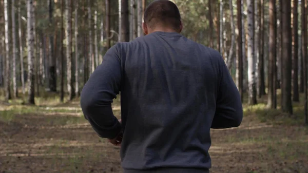 Muscular runner running on road through forest. Back view. Athletic man running on road through forest. Athletic man running on trail through autumn forest — Stock Photo, Image