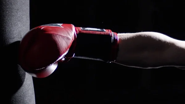 Combattente pratica alcuni calci con sacco da boxe Un uomo con un tatuaggio boxe su sfondo scuro. Calci, sacco da boxe su sfondo scuro. Sacco da boxe nero pesa in palestra — Foto Stock