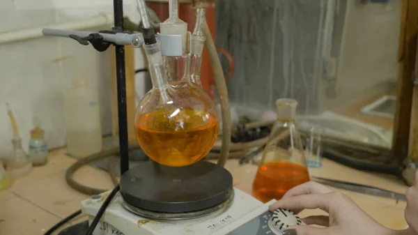 Scienziato che mischia liquidi in fiaschi in un laboratorio di ricerca. Attrezzature speciali per miscelare fluidi in laboratorio. Reagenti di miscelazione stagisti insieme nel pallone . — Foto Stock