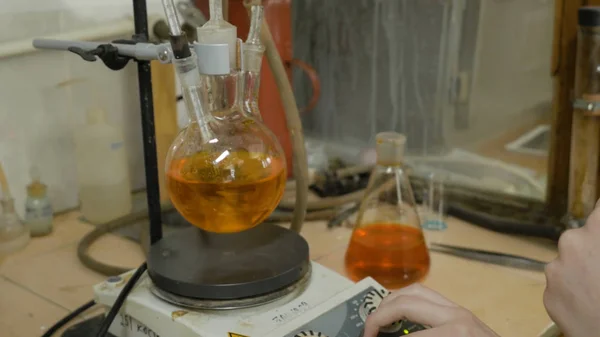 Scienziato che mischia liquidi in fiaschi in un laboratorio di ricerca. Attrezzature speciali per miscelare fluidi in laboratorio. Reagenti di miscelazione stagisti insieme nel pallone . — Foto Stock