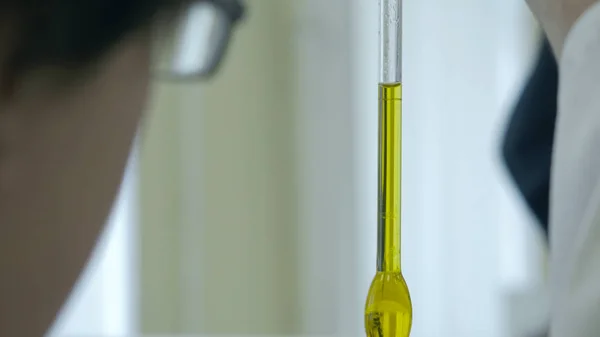 Cam tüp tıbbi test sırasında bilim adamı elinde mavi akışkan ile close-up. bir tüp yeşil kimyasal sıvı ile tutan bilim adamları el. Cam tüp bebek tutan bir araştırma bilim adamı parmak — Stok fotoğraf