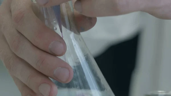 Hand gieten van vloeibare chemicaliën in de kolf. Lab werknemer mengen chemicaliën — Stockfoto