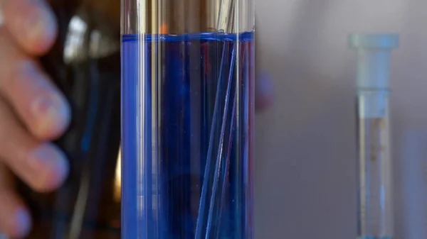 Ученый разливает химикаты голубого цвета во фляжку. здравоохранение и медицинская концепция. Ученые занимаются экспериментальной наукой, например, смешивают химикаты. — стоковое фото