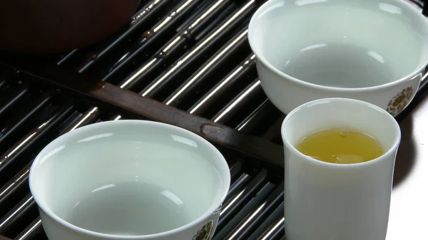 Prozess Brühtee, Teezeremonie, Tasse frisch gebrühten schwarzen Tee. Asiatischer Tee auf Bambusmatte, Nahaufnahme. der Chinese aus einer gegossenen Teekanne — Stockfoto