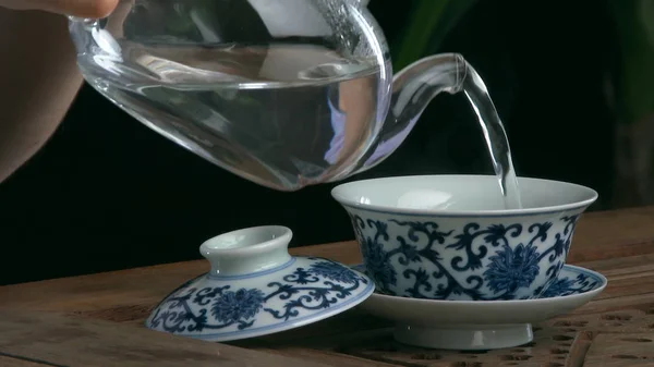 Process brewing tea,tea ceremony,Cup of freshly brewed black tea. Asian tea set on bamboo mat,Closeup. The chinese from a cast teapot — Stock Photo, Image