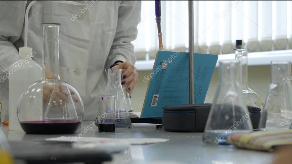 Lab technician doing experiment in lab. Male medical or scientific laboratory researcher performs tests with blue liquid. Scientist working with flasks in laboratory