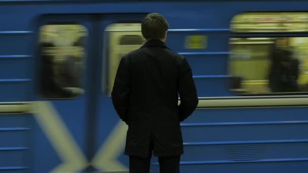 Metro istasyonunda yalnız genç adam arkadan. Genç adam bir tren metro, dikiz bekler — Stok video