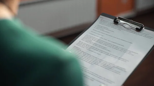 Mujer con tableta de carpetas y vista de texto desde atrás. Mujer de negocios con lápiz y carpeta de papel. Joven trabajadora bonita escribiendo algo en su vista de los periódicos desde atrás. Una mujer está sosteniendo carpeta azul para —  Fotos de Stock