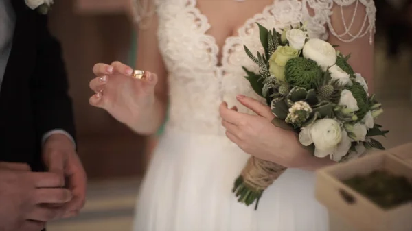 Closeup of a bride putting a gold wedding ring onto the grooms finger. wedding rings and hands of bride and groom. young wedding couple at ceremony. bride wear ring on grooms finger. — Stock Photo, Image