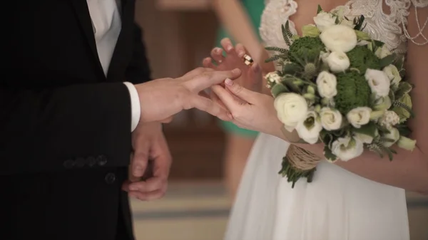 Κοντινό πλάνο μιας νύφης, βάζοντας ένα χρυσό γαμήλιο δαχτυλίδι επάνω το δάχτυλο γαμπρούς. Βέρες και τα χέρια της νύφης και του γαμπρού. ζευγάρι νέοι γαμήλια τελετή. νύφη φορούν δαχτυλίδι στο δάχτυλό γαμπρούς. — Φωτογραφία Αρχείου