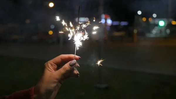 女性的手电光在街上。女人在大街上举行烟火的特写。特写镜头的烟火的女孩 — 图库照片