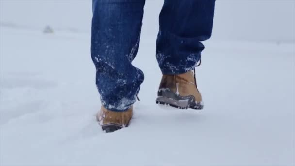 Чоловік йде снігом. Чоловік ходить по снігу, сліди від снігу, позаду. Чоловік ходить взимку в полі — стокове відео