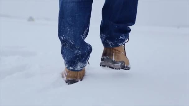 Man walking in snow. Man walking on snow, footprints in snow, behind. Man walks in the winter in the field — Stock Video