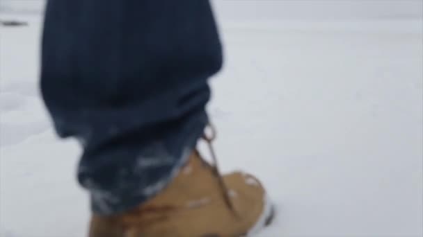 Man walking in snow. Man walking on snow, footprints in snow, behind. Man walks in the winter in the field — Stock Video