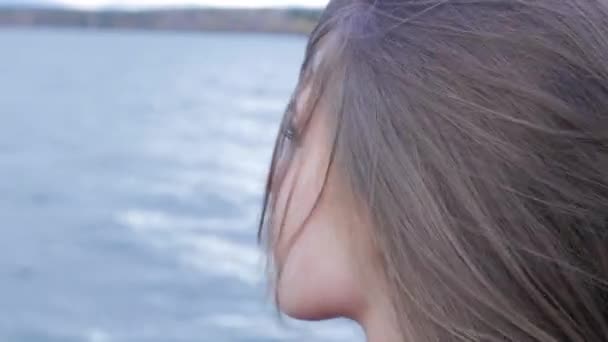 Et nærbilde av en vakker jente i sjøbakgrunn. exy kvinnelig modell i trendy solbriller en bakgrunn av innsjø. Avslappende ung kvinne i naturen – stockvideo