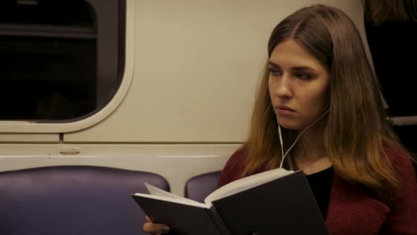 Piękna dziewczyna z książką w pociągu na stacji metra. Dziewczyna nastolatek, poczytać książkę w pociągiem lub samochodem — Wideo stockowe