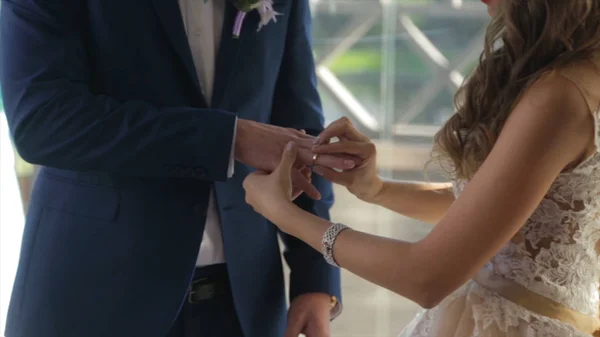 新娘把金戒指放到新郎手指上的特写镜头。结婚戒指，新娘和新郎手中。年轻的新婚夫妇在典礼上。新娘在新郎的手指上戴戒指. — 图库照片