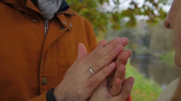 Ein Mann wärmt Frauenhände. Braut und Bräutigam halten sich Händchen und wärmen sich im Park. Mann und Frau Händchen haltend. Hände wärmen. — Stockfoto