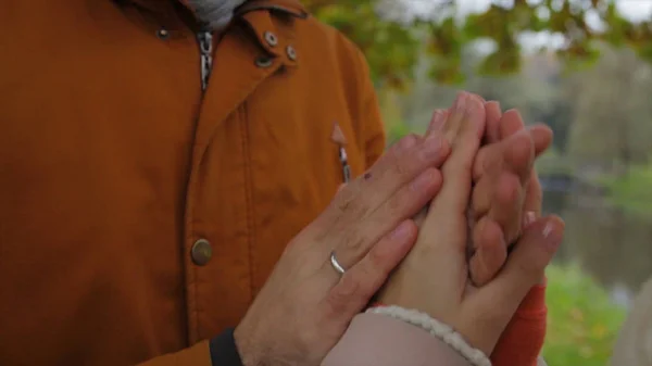 Ein Mann wärmt Frauenhände. Braut und Bräutigam halten sich Händchen und wärmen sich im Park. Mann und Frau Händchen haltend. Hände wärmen. — Stockfoto