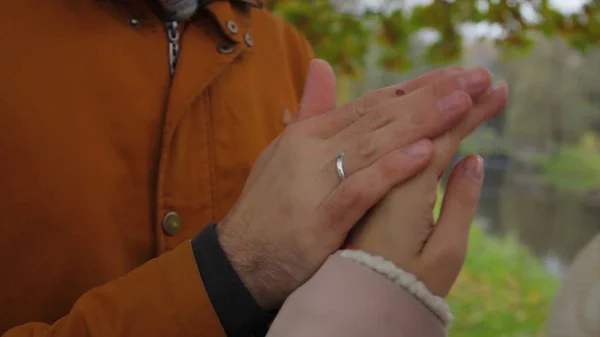 男人温暖女人的手。新娘和新郎手牵手, 在公园里互相温暖。男人和女人牵手。温暖的手. — 图库照片