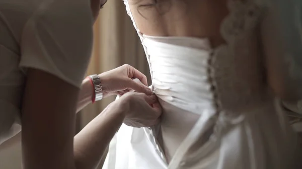 Stilvolle schöne Brautjungfern helfen wunderschöne brünette Braut in weißem Kleid machen sich bereit für die Hochzeit, morgendlichen Vorbereitungen, Frau Kleid anziehen. Mutter und Brautjungfer, helfen, ein Hochzeitskleid zu kleiden — Stockfoto
