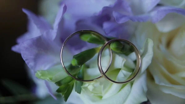 Anelli nuziali su un mazzo di fiori bianchi vicino. Anelli nuziali e bouquet di fiori blu scuro. Chiudete. Matrimonio. Focus selettivo — Foto Stock