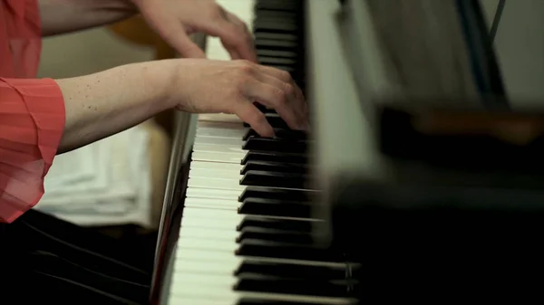 Κορίτσια τα χέρια στο πληκτρολόγιο του πιάνου. Το κορίτσι παίζει πιάνο, κλείστε επάνω πιάνο. Τα χέρια τα άσπρα πλήκτρα της παίζοντας πιάνο μια μελωδία. Γυναικεία χέρια στο πληκτρολόγιο, παίζει τη μελωδία σημειώσεις. — Φωτογραφία Αρχείου