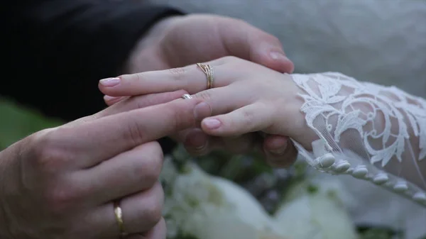 Braut trägt Ring am Finger des Bräutigams. Der Bräutigam legt der Braut den Ehering an den Finger. eheliche Hände mit Ringen. Birde trägt den Ring am Finger des Bräutigams — Stockfoto