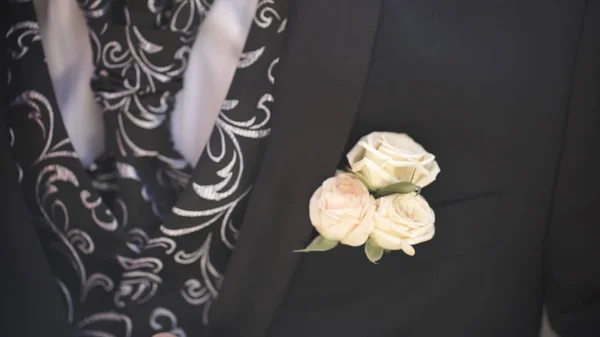 Carnation flower in a pocket. the flower in jacket pocket. pin with decorative white flowers pinned on the grooms jacket. boutonniere flower in the pocket of the groom on wedding ceremony