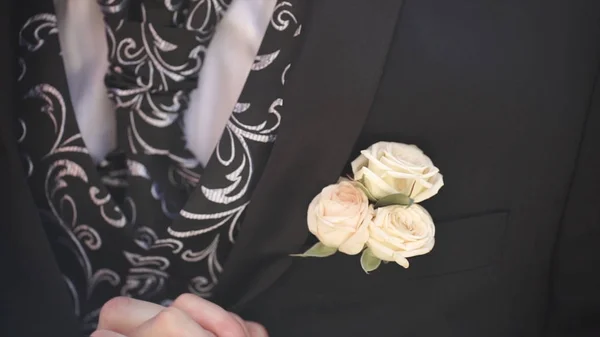 Carnation flower in a pocket. the flower in jacket pocket. pin with decorative white flowers pinned on the grooms jacket. boutonniere flower in the pocket of the groom on wedding ceremony