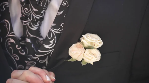 Carnation flower in a pocket. the flower in jacket pocket. pin with decorative white flowers pinned on the grooms jacket. boutonniere flower in the pocket of the groom on wedding ceremony