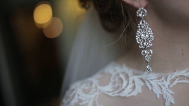 Güzel gelin küpe üzerinde koyar. Güzellik modeli kız takı evlilik için giyiyor. Düğün kadın portre. Kadın kıvırcık saç ve dantel örtü ile. Takı ve güzellik kavramı - giyen yakın