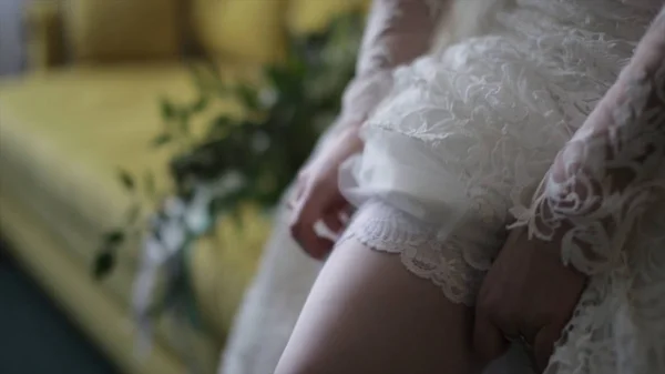 Sposa veste calze a piedi. Sposa di bellezza in un vestito che indossa calze da sposa all'interno. Ritratto femminile bella signora in un vestito. Primo piano delle mani della donna — Foto Stock